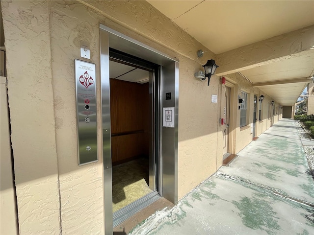 property entrance featuring elevator and stucco siding