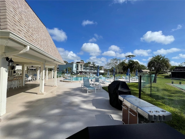 view of patio / terrace with a community pool, fence, and area for grilling