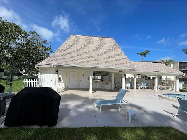 exterior space with a swimming pool, fence, outdoor dry bar, and a grill