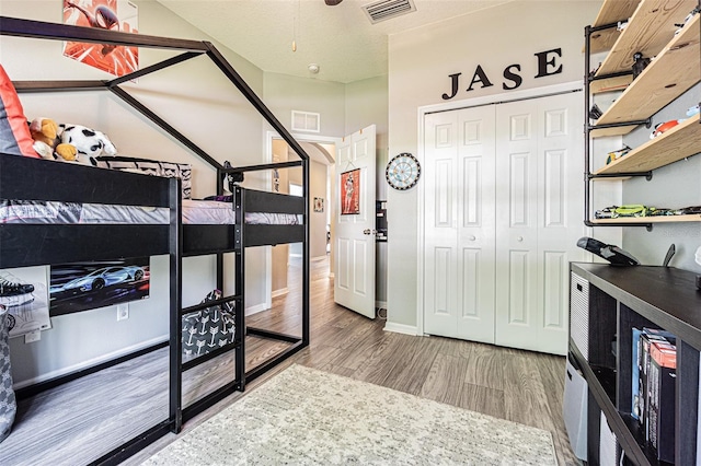 bedroom with a closet, baseboards, visible vents, and wood finished floors