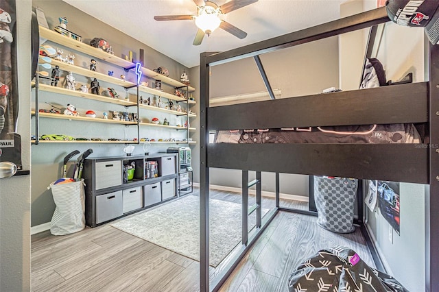 bedroom with a ceiling fan, wood finished floors, and baseboards