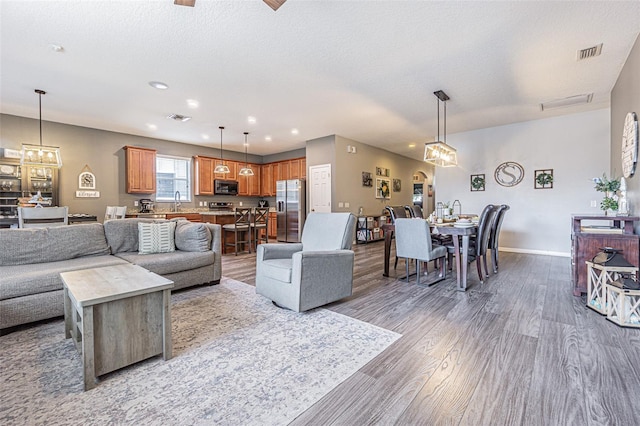 living room featuring recessed lighting, baseboards, visible vents, and wood finished floors