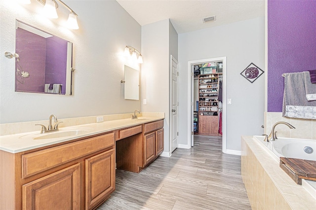 full bathroom with visible vents, a sink, a garden tub, double vanity, and a spacious closet