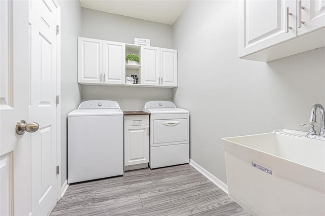 laundry room featuring light wood-style flooring, baseboards, a sink, washing machine and clothes dryer, and cabinet space