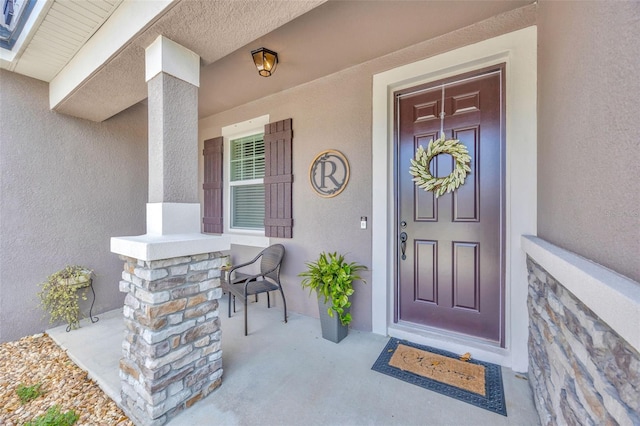 entrance to property with stucco siding and covered porch
