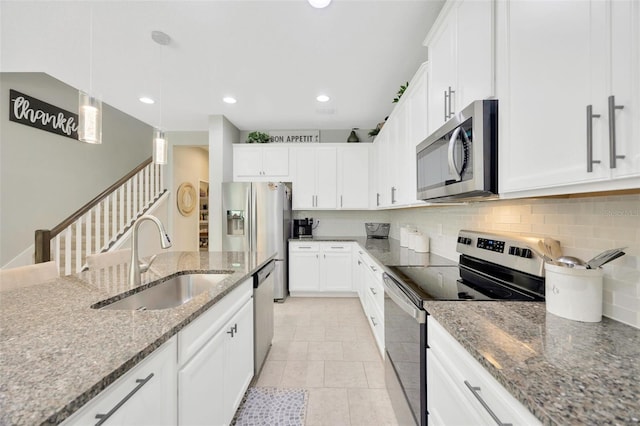 kitchen featuring a sink, stainless steel appliances, decorative light fixtures, white cabinetry, and backsplash