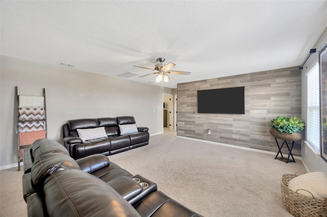 carpeted living room featuring baseboards, visible vents, ceiling fan, and an accent wall