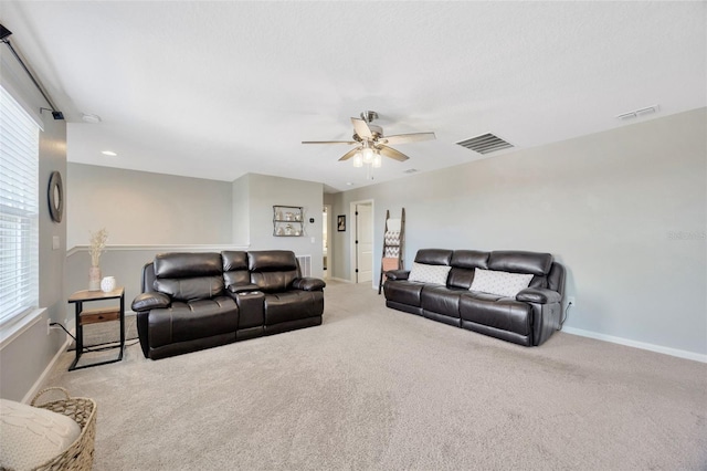carpeted living room with visible vents, a ceiling fan, and baseboards