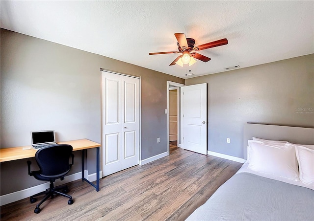 bedroom with ceiling fan, a closet, visible vents, wood finished floors, and baseboards