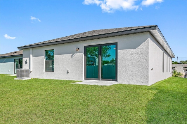 back of house with a lawn, stucco siding, and central AC