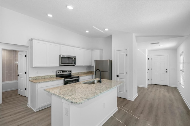 kitchen featuring light wood-type flooring, white cabinetry, a kitchen island with sink, appliances with stainless steel finishes, and a sink