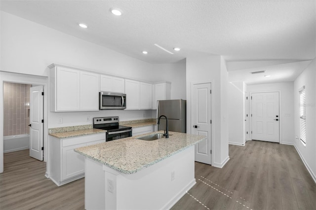 kitchen featuring a sink, light wood-type flooring, white cabinetry, a center island with sink, and stainless steel appliances