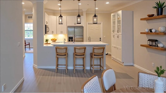 kitchen featuring white cabinets, light countertops, stainless steel appliances, a peninsula, and a kitchen bar