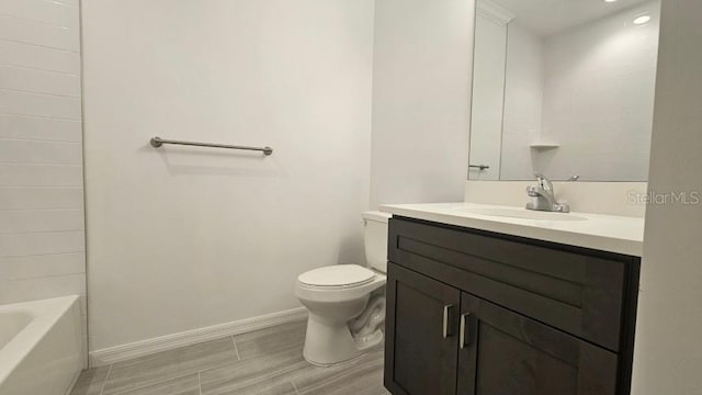 bathroom featuring baseboards, wood finished floors, toilet, and vanity
