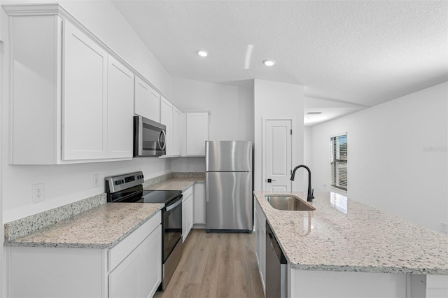 kitchen featuring light wood-style flooring, recessed lighting, appliances with stainless steel finishes, a kitchen island with sink, and a sink