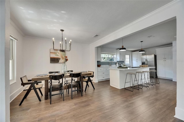 2920 N 11th St, Tampa, FL 33605 - dining area with a notable chandelier, baseboards, crown molding, visible vents, and wood finished floors