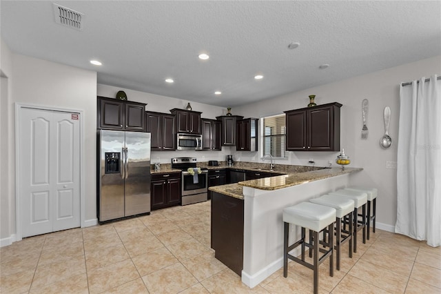 1401 Wexford Way, Davenport, FL 33896 - kitchen with appliances with stainless steel finishes, visible vents, a kitchen bar, recessed lighting, and a peninsula