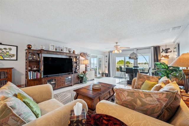 living room featuring visible vents, a textured ceiling, and a ceiling fan