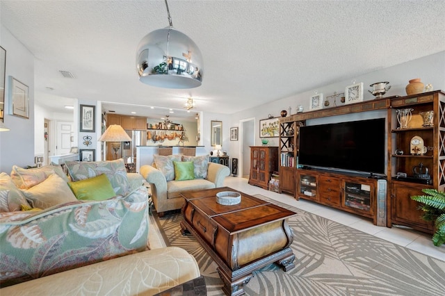 living room with visible vents, light tile patterned floors, and a textured ceiling