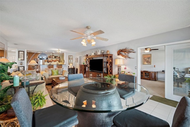 dining space featuring tile patterned floors, a textured ceiling, a ceiling fan, and carpet floors