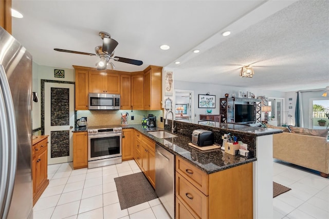 kitchen featuring a peninsula, a ceiling fan, a sink, stainless steel appliances, and open floor plan