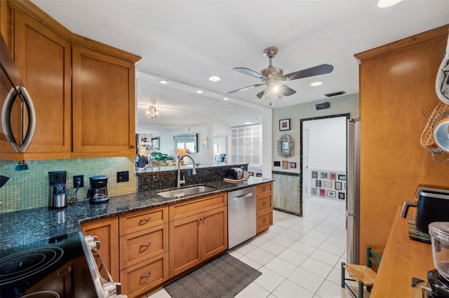 kitchen with ceiling fan, brown cabinetry, appliances with stainless steel finishes, a sink, and backsplash