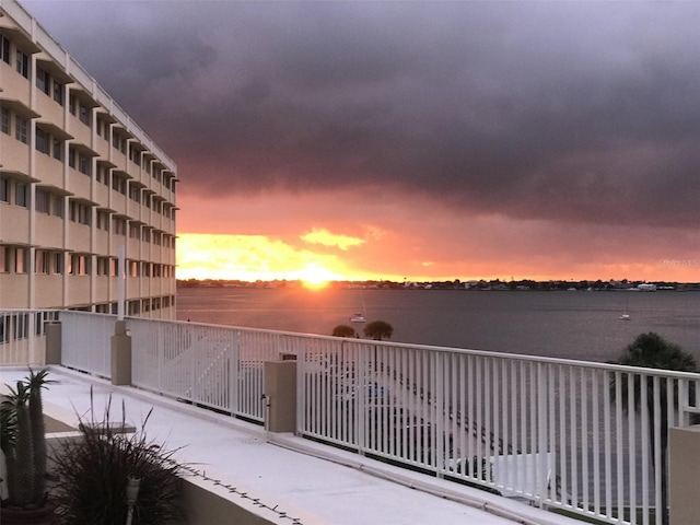 balcony at dusk featuring a water view