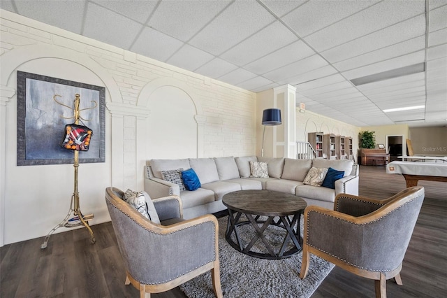 living area with a paneled ceiling and wood finished floors