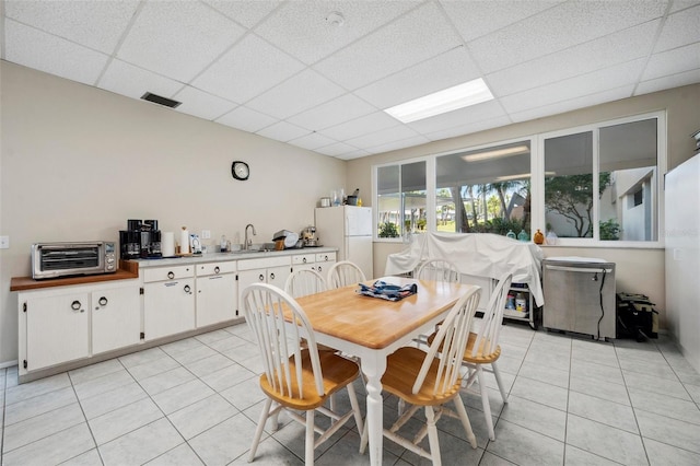 dining area featuring a paneled ceiling, light tile patterned floors, a toaster, and visible vents