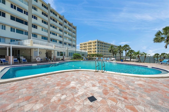 community pool with a patio area and fence