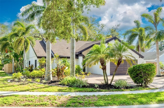 view of front facade featuring a shingled roof, an attached garage, and driveway