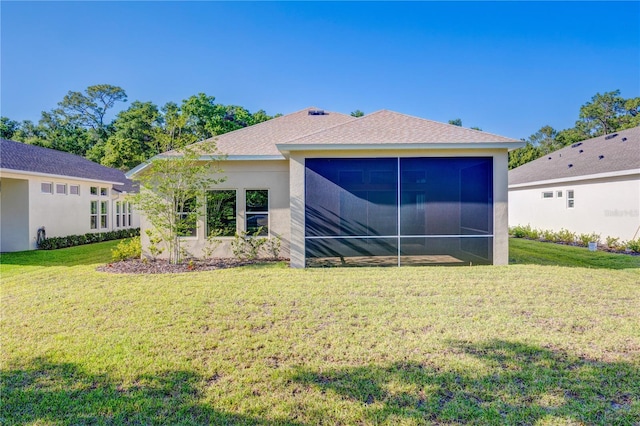 back of house featuring stucco siding, a sunroom, and a lawn
