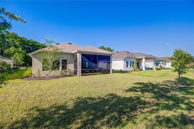 rear view of house featuring a yard, stucco siding, and a sunroom