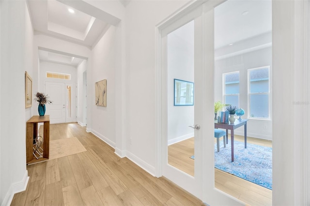 corridor with light wood finished floors, visible vents, and baseboards