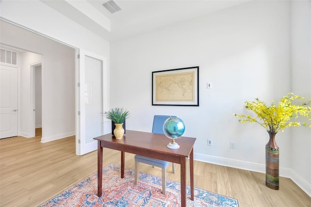 office space with light wood-style floors, visible vents, and baseboards