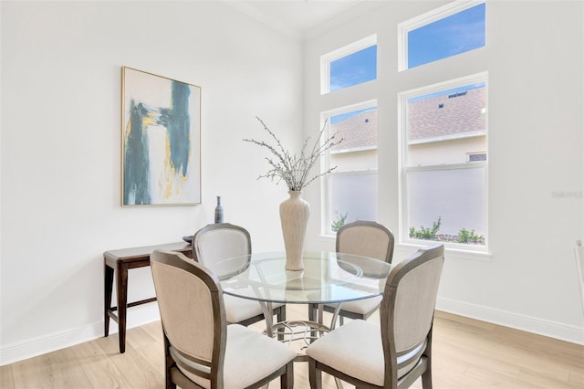 dining space with light wood-type flooring, baseboards, and crown molding