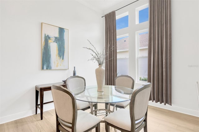 dining area with ornamental molding, baseboards, and light wood-style floors