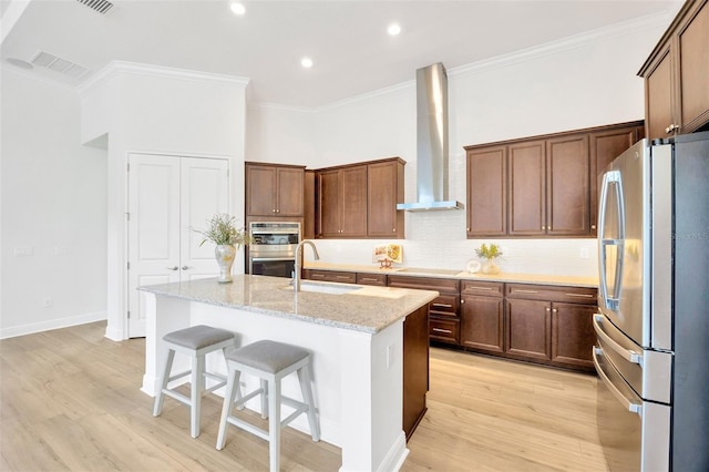 kitchen featuring wall chimney range hood, ornamental molding, a sink, stainless steel appliances, and backsplash
