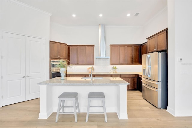 kitchen with crown molding, a sink, wall chimney range hood, and stainless steel appliances