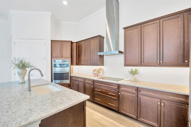 kitchen with crown molding, wall chimney exhaust hood, a sink, black electric stovetop, and stainless steel double oven