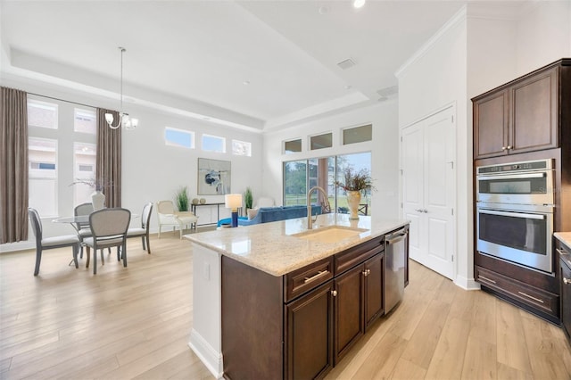 kitchen with light wood-style flooring, a tray ceiling, a sink, and appliances with stainless steel finishes