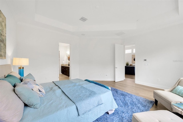 bedroom featuring baseboards, light wood-type flooring, crown molding, visible vents, and a raised ceiling