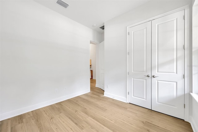 unfurnished bedroom with visible vents, baseboards, light wood-type flooring, and a closet