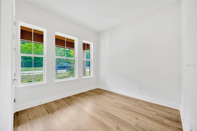 empty room with light wood-style flooring, baseboards, and plenty of natural light