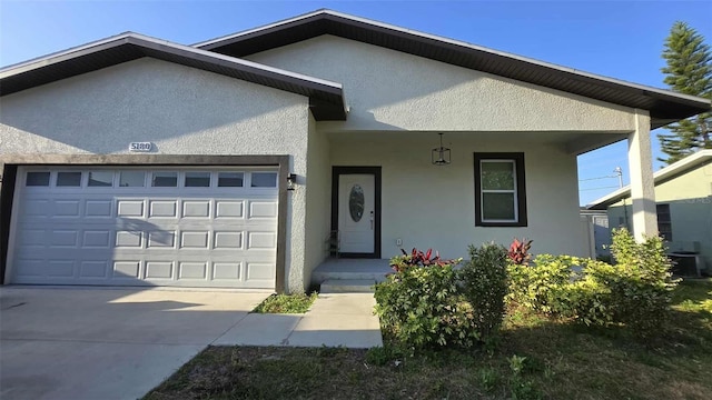 ranch-style house with an attached garage, concrete driveway, stucco siding, and covered porch