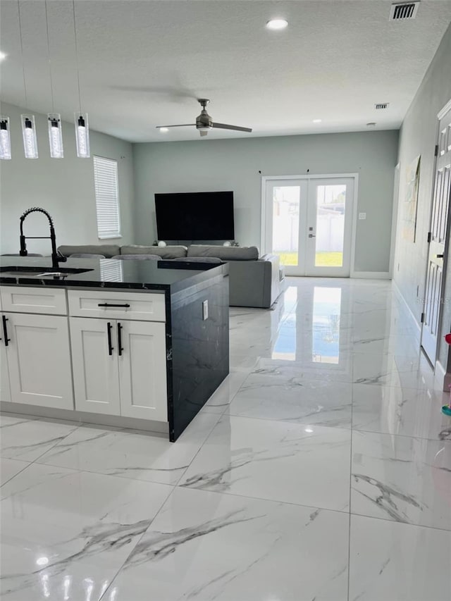 kitchen featuring marble finish floor, dark countertops, ceiling fan, white cabinetry, and french doors