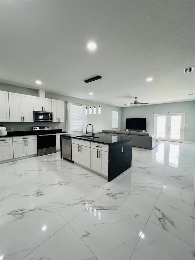 kitchen with visible vents, stainless steel appliances, dark countertops, and open floor plan