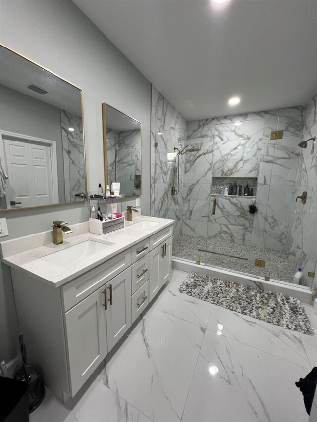 full bath with a marble finish shower, a sink, double vanity, and marble finish floor
