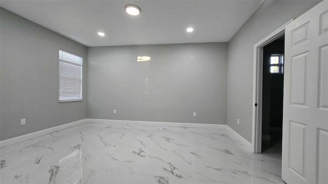 empty room with baseboards, recessed lighting, a wealth of natural light, and marble finish floor