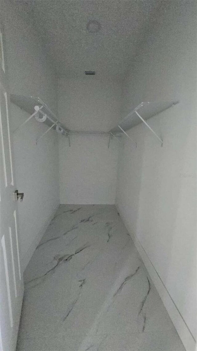 walk in closet featuring marble finish floor